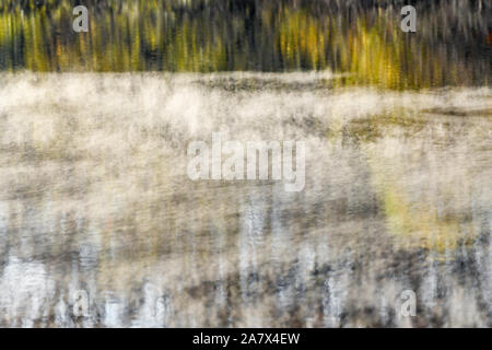 Fall leaves reflected in water - fall colors - fall trees reflecting - impressionism - impressionist photography - steam fog - misty water Stock Photo