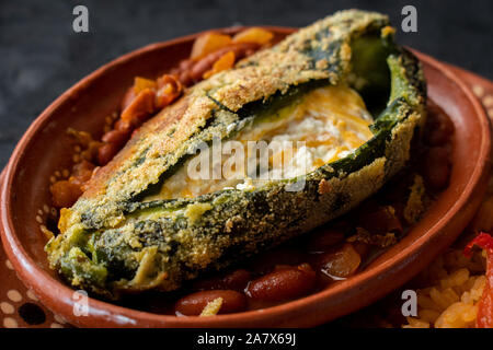 Chilles rellenos and Mexican rice served in traditional clay plates Stock Photo