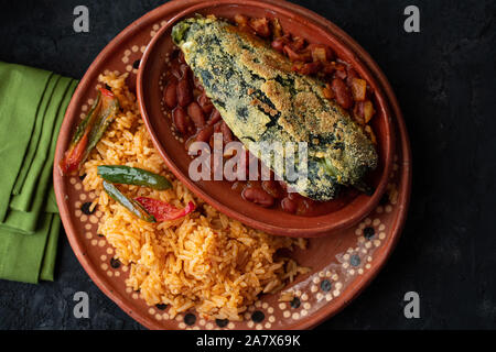 Chilles rellenos and Mexican rice served in traditional clay plates Stock Photo