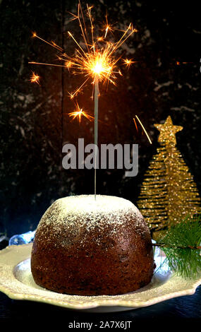 Christmas pudding, English style holiday dessert, with festive sparkler on dark marble counter background. Stock Photo