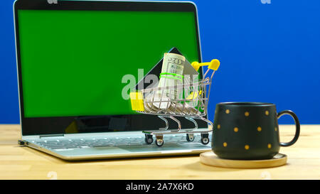 Black Friday Cyber Monday e-commerce retail shopping concept with miniature shopping cart and modern laptop against chroma key background, with negati Stock Photo