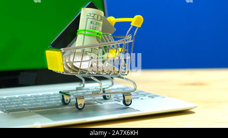 Black Friday Cyber Monday e-commerce retail shopping concept with miniature shopping cart and modern laptop against chroma key background, with negati Stock Photo