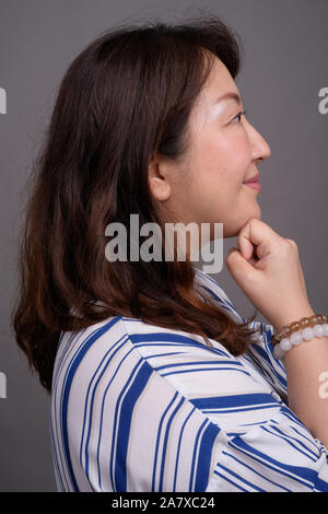 Profile view of mature beautiful Asian businesswoman thinking Stock Photo