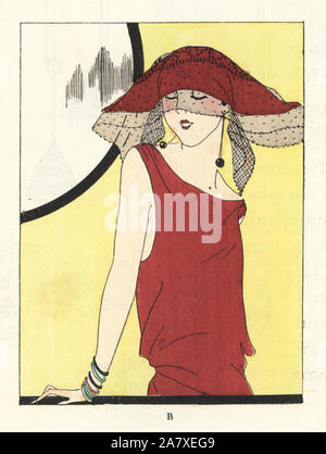 Woman in red dress and red toque hat decorated with a lace veil standing in front of a mirror. Handcolored pochoir (stencil) lithograph from the French luxury fashion magazine Art, Gout, Beaute, 1923. Stock Photo