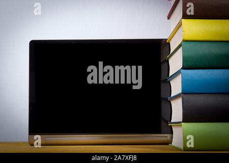 Stack of books with multi-colored binders and a tablet on a wooden table Stock Photo