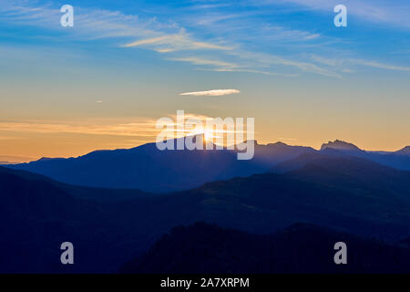 Sunrise from behind a mountain range. Silhouettes of mountains against the sky. Panorama of the mountains at sunrise. Stock Photo