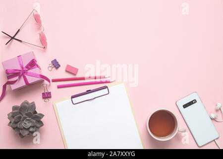Women day gift, office desk. Gift box, mobile phone and tea cup against pink background, copy space Stock Photo