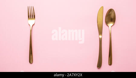 Gold and pink luxury table setting. Golden cutlery set against pink background. Top view, copy space Stock Photo