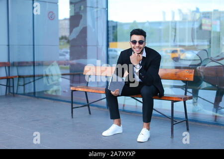 Man in suit arabic puts on sunglasses with tablet near business center Stock Photo
