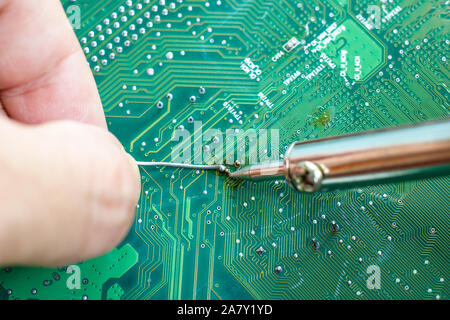 Technicians are using a soldering iron for repairing electronic of the computer circuit board concept technology of computer circuit hardware. Stock Photo