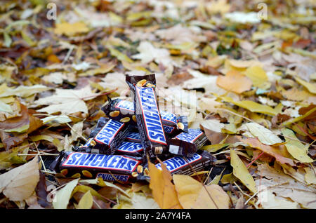 KHARKOV, UKRAINE - OCTOBER 17, 2019: Snickers chocolate bars in brown wrapping lies on autumn leaves background Stock Photo