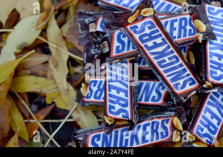 KHARKOV, UKRAINE - OCTOBER 17, 2019: Snickers chocolate bars in brown wrapping lies on autumn leaves background Stock Photo