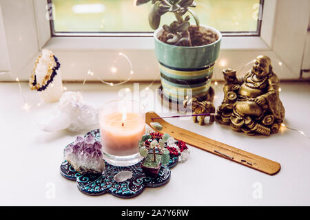 Feng Shui altar at home in living room or bed room. Attracting wealth and prosperity concept. Crystal clusters, wire tree with gemstones, golden smili Stock Photo