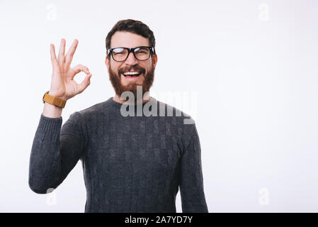 Happy smiling handsome man with beard wearing eyeglasses and showing OK gesture Stock Photo