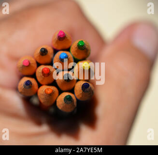 Pencils of different colours, held tightly in hand. Stock Photo