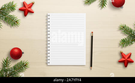 Notebook on work desk surrounded by Christmas decorations. Concept of planning goals for the new year. Empty, blank paper for text. Top view, flat lay Stock Photo