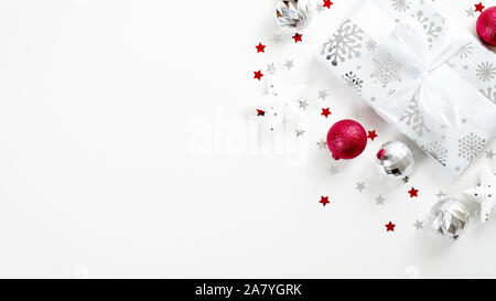 Stylish silver Christmas gift box with ribbon bow and Xmas red decorations on white background with copy space. Winter holidays greeting card template Stock Photo