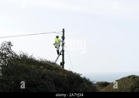 BT Openreach Engineer Working at Height on a Telegraph Pole in a Rural Area, Cornwall, UK Stock Photo