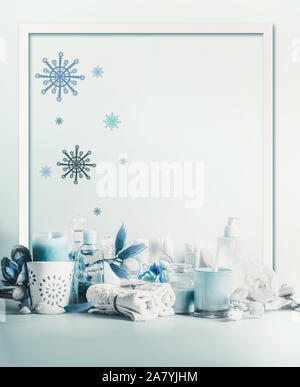 Winter spa and wellness concept. Winter skin and body care. Cosmetic products. Holiday spa day. Frame. Blue composition of candles, towels, and flower Stock Photo