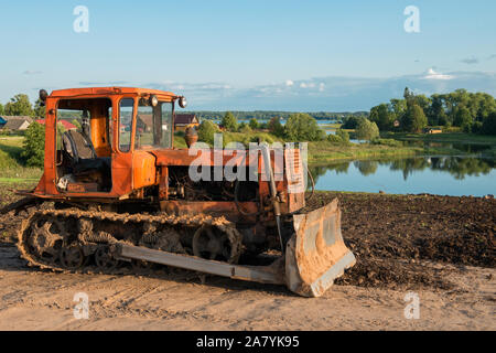Caterpillar agricultural tractor DT-75 in the countryside, on the lake. Lake Focus Stock Photo