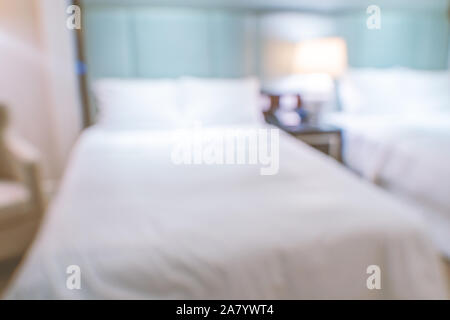 Clean and cozy modern hotel bedroom interior with double bed, abstract defocused blur with bokeh background, design concept of luxury trip. Stock Photo