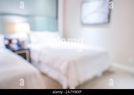 Clean and cozy modern hotel bedroom interior with double bed, abstract defocused blur with bokeh background, design concept of luxury trip. Stock Photo