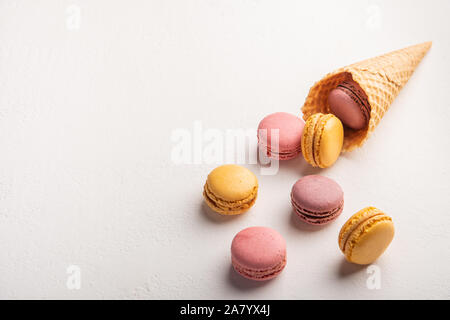 Macarons poured out of pastry cone on white background. Top view Stock Photo