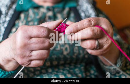 Old woman knitting in home near the window. Selective focus Stock Photo