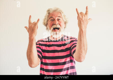 Happy and crazy senior old man with rock'n roll hand sign - alternative mature caucasian portait people have fun -youthful retired male with white bac Stock Photo