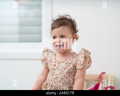 1 year old baby girl stands in her cot (or crib) Stock Photo