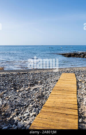 Wooden board walkway over stony beach at La Caleta, Costa Adeje, Tenerife, Canary Islands, Spain Stock Photo