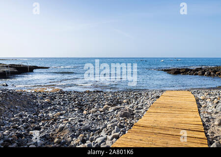 Wooden board walkway over stony beach at La Caleta, Costa Adeje, Tenerife, Canary Islands, Spain Stock Photo
