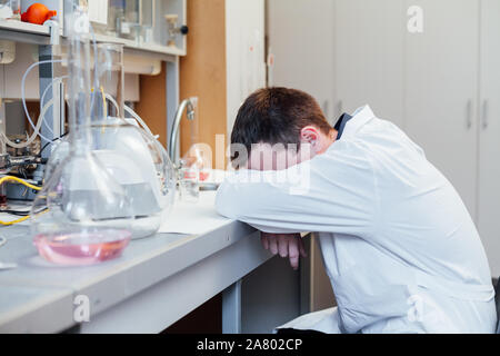 Male scientist sleeps in medical chemical lab Stock Photo