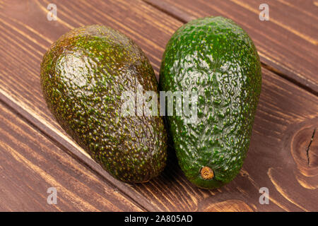 Group of two whole fresh green avocado on brown wood Stock Photo