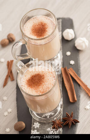 Eggnog in glass cups with a delicate foam, spices and a cinnamon stick Stock Photo