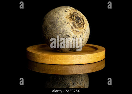 One whole raw red beetroot on bamboo coaster isolated on black glass Stock Photo