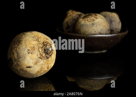 Group of four whole raw red beetroot in dark ceramic bowl isolated on black glass Stock Photo