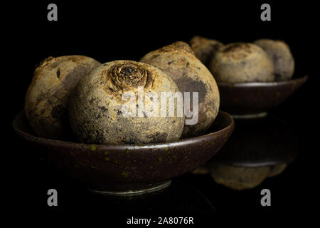 Group of six whole raw red beetroot in dark ceramic bowl isolated on black glass Stock Photo