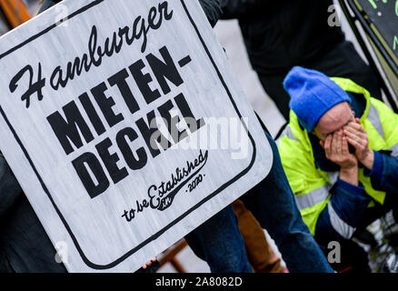 Hamburg, Germany. 05th Nov, 2019. A participant of the Hamburg alliance 'Recht auf Stadt Netzwerk' kneels next to an oversized beer mat with the inscription 'Hamburger Mietendeckel - to be established 2020'. The alliance presented its ideas for a possible rent cover at the Hamburg town hall market. Credit: Axel Heimken/dpa/Alamy Live News Stock Photo