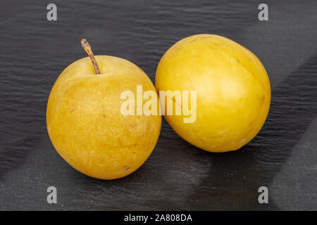 Group of two whole fresh yellow plum flatlay on grey stone Stock Photo