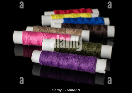 Group of eight whole sewing thread spool isolated on black glass Stock Photo