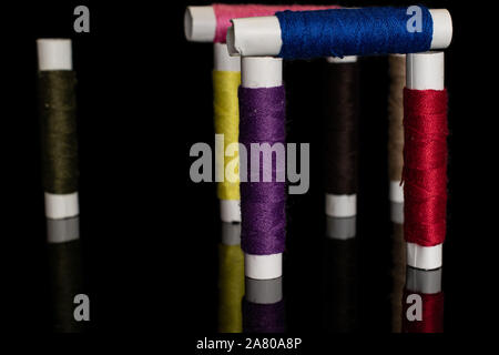 Group of eight whole colorful sewing thread spool isolated on black glass Stock Photo