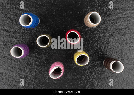 Group of eight whole sewing thread spool flatlay on grey stone Stock Photo