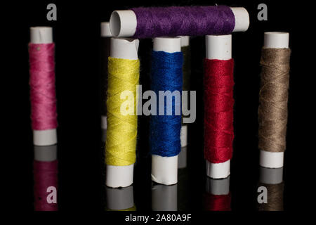 Group of eight whole standing sewing thread spool isolated on black glass Stock Photo