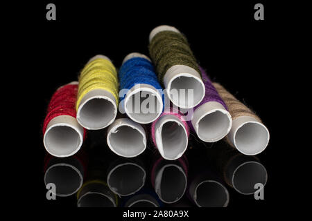 Group of eight whole sewing thread spool isolated on black glass Stock Photo