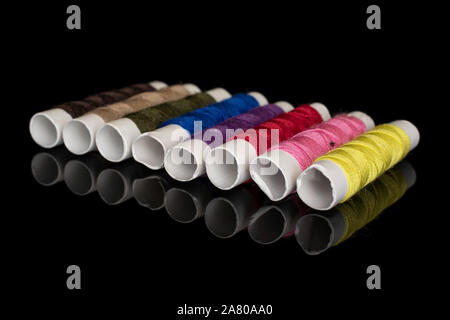 Group of eight whole sewing thread spool diagonal isolated on black glass Stock Photo