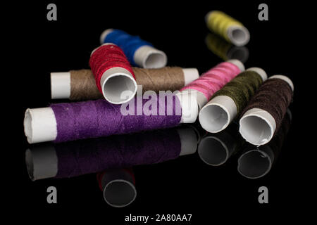 Group of eight whole sewing thread spool isolated on black glass Stock Photo