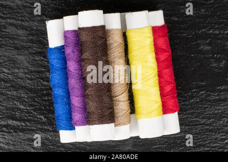 Group of seven whole sewing thread spool flatlay on grey stone Stock Photo