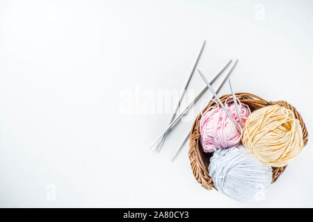 Pastel colored skein of thread for knitting and knitting needles in a small basket. Needlework background. On white background copy space Stock Photo