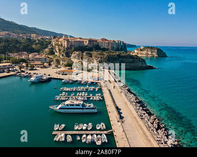 Aerial view of boats moored at the Port of Tropea, Calabria, Italy. Houses overlooking the sea. Beach and Sanctuary on the horizon. Italian coasts Stock Photo